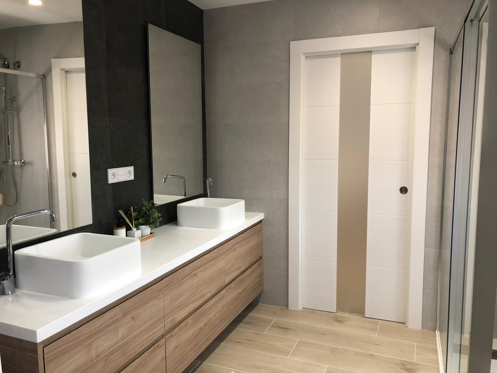 Mueble de baño a medida en madera con dos lavabos sobre encimera blanca y espejos