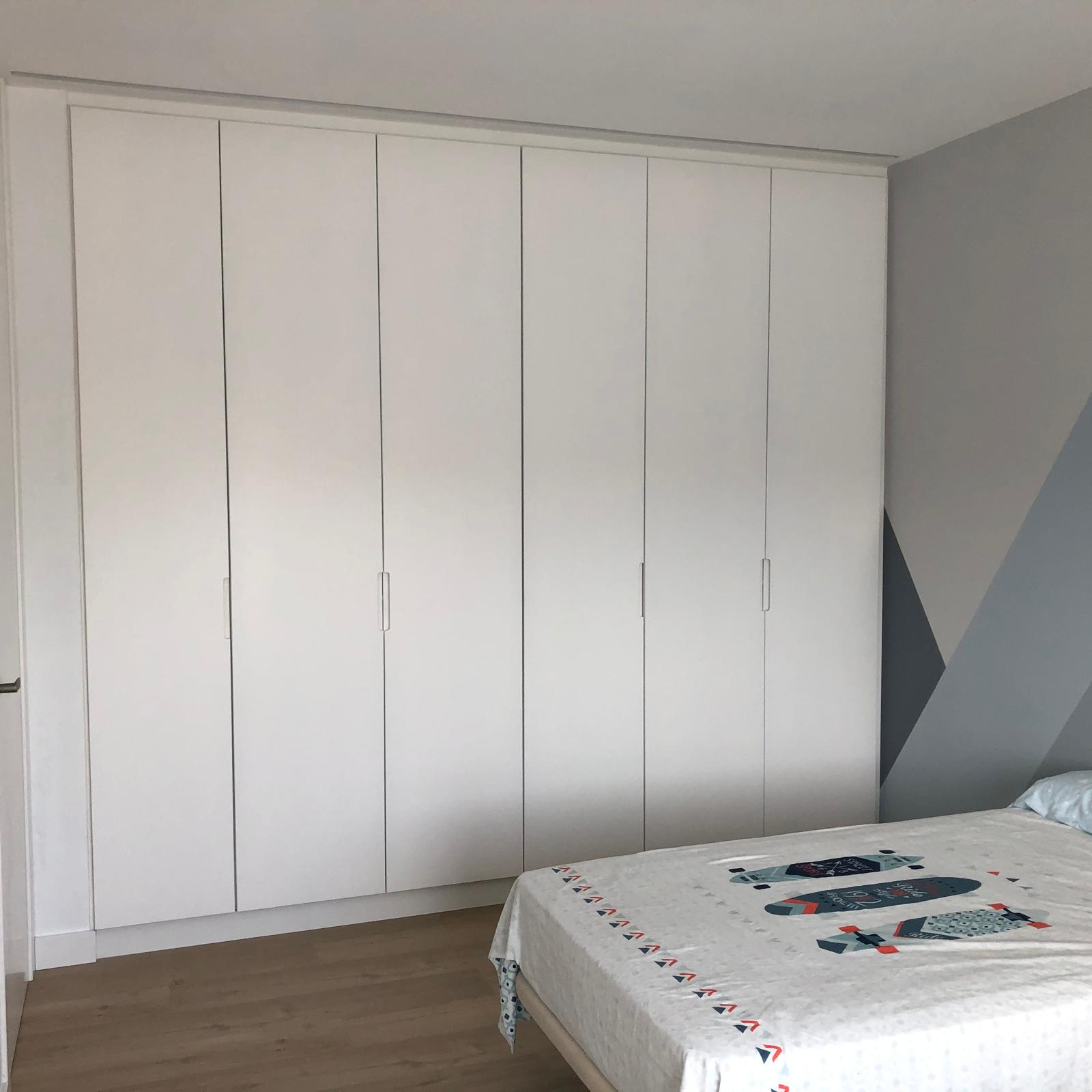 Armario empotrado blanco de seis puertas integrado en dormitorio