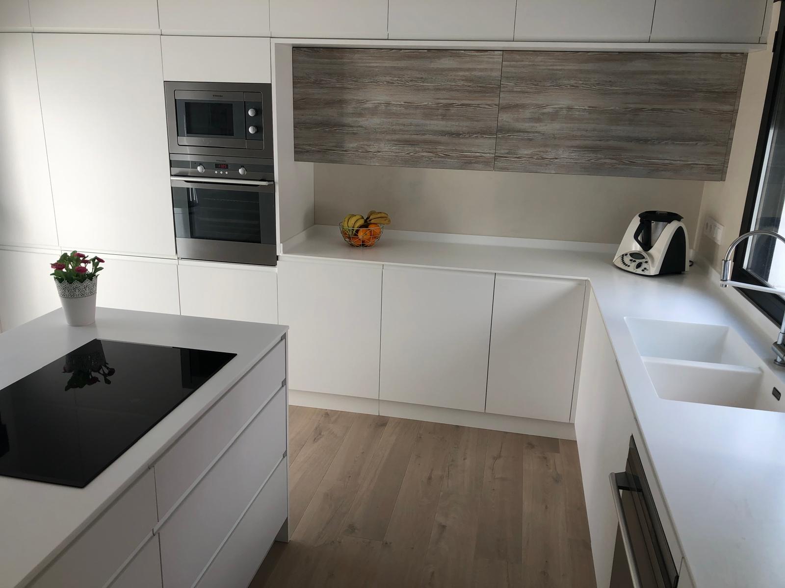 Cocina blanca a medida con isla y módulos altos en acabado madera