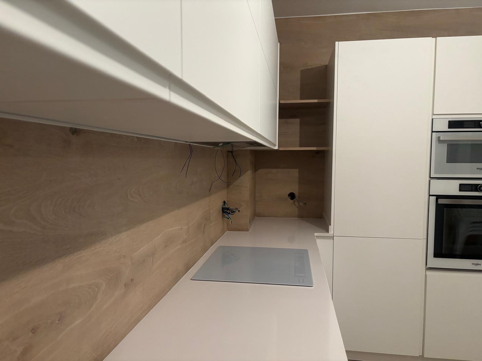 Encimera blanca y frontal de madera de una cocina a medida en instalación