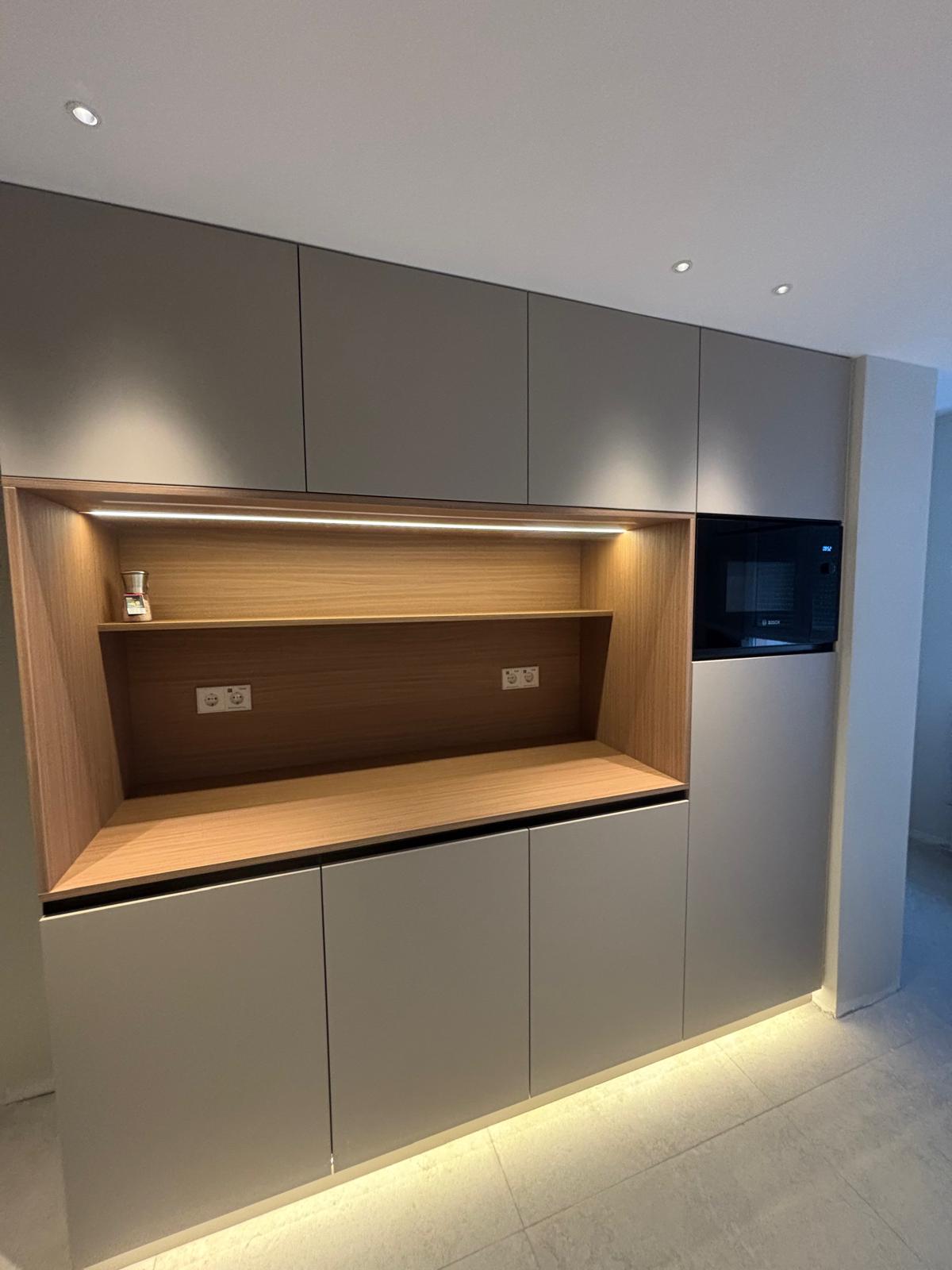Mueble de office a medida con hueco central en madera, iluminación LED y microondas integrado