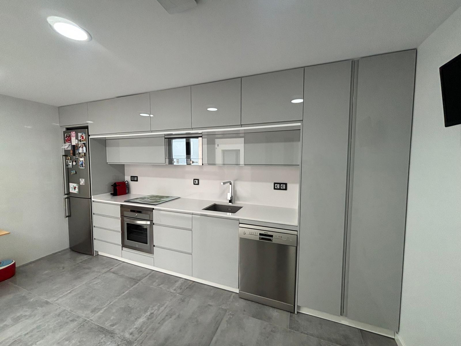 Cocina completa a medida en gris claro con armarios hasta el techo